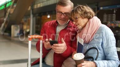 时尚的退休夫妇在火车站<strong>翻阅</strong>他们的手机照片。 旅途愉快