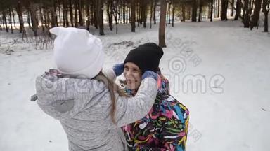 妈妈把她的小女儿抱在怀里，在冬天把她的帽子拉直。