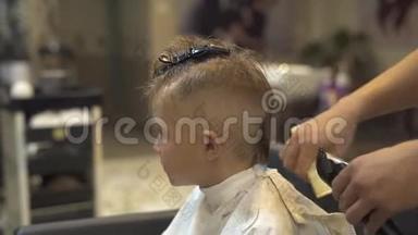 理发师在理发店用电动剃须刀给小男孩理发。 孩子们在理发机上理发