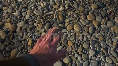 POV. 第一个人的视频。 一个人`手拿着一块光滑的海石扔进海里。
