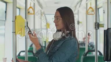一个年轻微笑的女人在电车上用智能<strong>手机支付</strong>免费的公共交通。