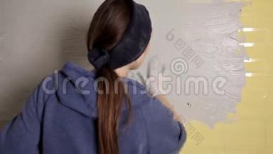家庭修理。 女孩用一个大金属抹子把石膏铺在墙上，使墙上的石膏填料对齐