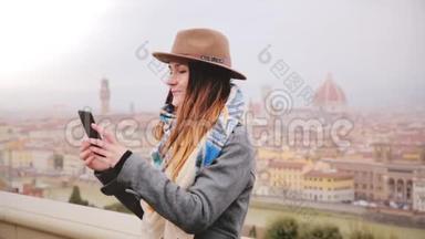 快乐微笑的旅游女孩在惊人的城市景观全景拍摄智能手机自拍照片秋季雾佛罗伦萨，意大利。