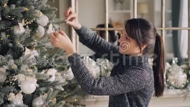 <strong>创意</strong>棕发<strong>正</strong>在装饰圣诞树，触摸美丽的球和照明，聚会