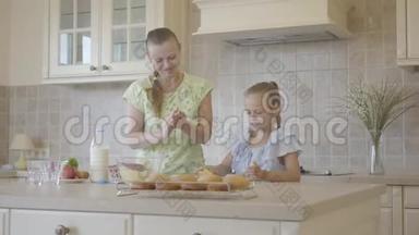 <strong>漂亮</strong>的年轻<strong>妈妈</strong>和可爱的小女儿一起在厨房做饭。 真正幸福的家庭。 关系<strong>妈妈</strong>和