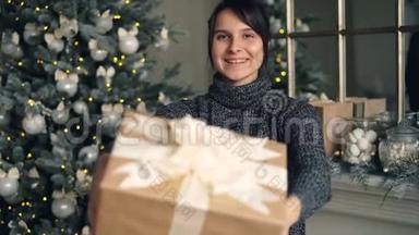微笑的女孩拿着礼物盒，然后伸展双手，献上圣诞礼物的画像