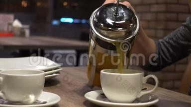 咖啡屋里的女人用杯子从法国媒体上倒出沙棘茶，双手特写。