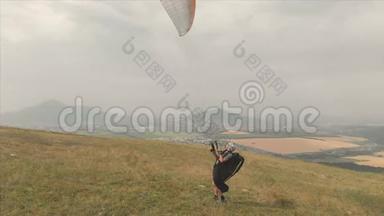 专业滑翔伞的鸟瞰图从山坡上起飞。 滑翔伞运动