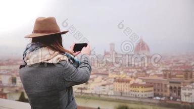 快乐的旅游女孩拍摄智能手机照片，令人惊奇的全景冬季多雨佛罗伦萨，意大利，步行离开。