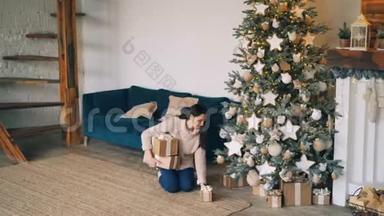 穿着暖和毛衣的漂亮女孩正把礼物盒带到圣诞<strong>树下</strong>，放在冷杉<strong>树下</strong>，然后微笑着
