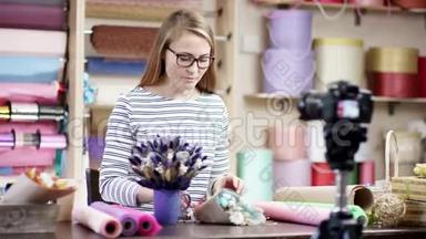 年轻的花艺师在花店用纸包花，做一个视频<strong>课</strong>。 她<strong>试</strong>图把花编成