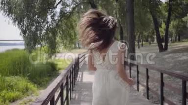 可爱的年轻女孩，一头黑发，戴着太阳镜，穿着白色的<strong>夏季</strong>时装<strong>长裙</strong>，穿在木桥上
