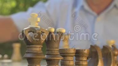 老人在桌旁的花园里准备<strong>棋局</strong>，把白色的数字放在他们的位置上