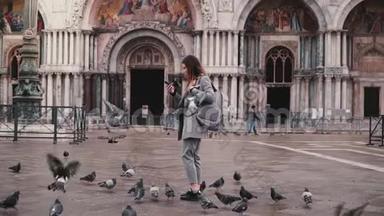 鸽子坐在美丽的女游客的手臂与智能手机附近<strong>圣马可</strong>大<strong>教堂</strong>在威尼斯，意大利慢动作。