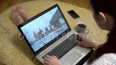 年轻女孩坐在地毯上的家里，用手提电脑屏幕观看街舞视频