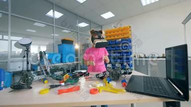 女孩站在一张有玩具的桌子附近，戴着360VR眼镜。 4K