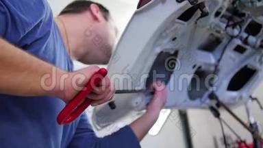 无漆凹痕修补.. 一位男主人正在修理汽车引擎盖上的凹痕，没有用优质的钩针作画