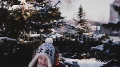 令人惊叹的特写镜头，可爱的小女孩穿着冬天的衣服，从雪松树后面跑到镜头前，慢动作。