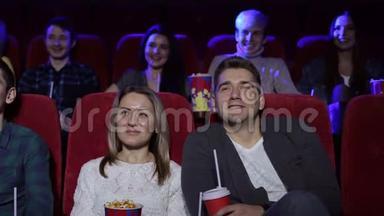 积极的夫妇在电影院喝可乐和吃爆米花。