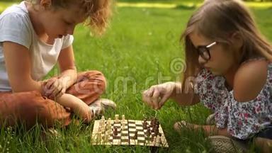 学校假期，青少年智力游戏。 两个十几岁的女朋友在公园里下棋，坐在草地上