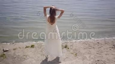 肖像迷人的年轻女孩，留着长长的黑发，穿着一件白色的<strong>夏季</strong>时装<strong>长裙</strong>，站在河边