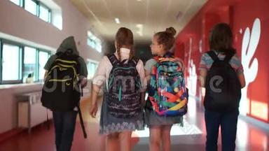 学生穿过学校走廊。 两个男孩和两个女孩。 孩子们背背包。 回学校去。 背面