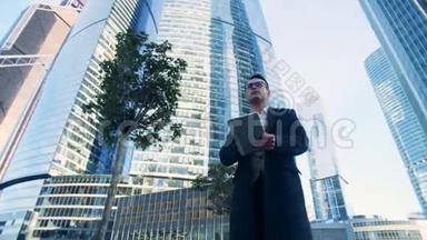 男经理正在沿着由摩天大楼组成<strong>的</strong>商业综合体散步。 6K<strong>电影院的</strong>镜头。