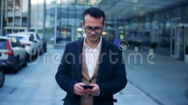 一位微笑<strong>的</strong>商人带着智能手机沿着现代城市街道行走<strong>的</strong>正面景色。 6K<strong>电影院的</strong>镜头。