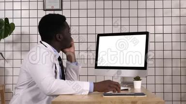 年轻的非洲医生在看他电脑的显示器。 白色显示器。