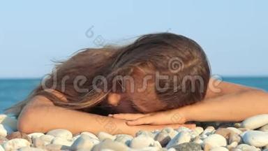 在海边微笑的年轻女孩。 躺在鹅卵石滩上微笑女孩的肖像