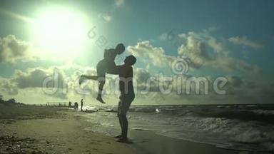一位年轻的<strong>父亲和</strong>他的<strong>儿子</strong>沿着海滨散步。 阳光灿烂. 爸爸把他的<strong>儿子</strong>扔到空中。 家庭
