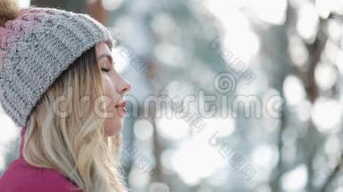 戴着冬帽的漂亮女人喜欢站在外面森林里的雪。 她微笑着，深吸一口气