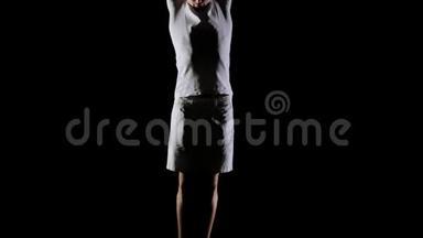 年轻英俊的男杂技演员穿着白色衣服在黑色背景下做跳跃和<strong>展示旋转</strong>技巧