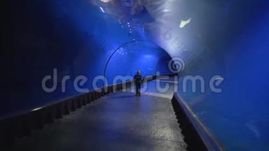 旅游<strong>儿童</strong>走在水族馆的隧道里，欣赏地看着不同的鱼在蓝水中<strong>游泳</strong>