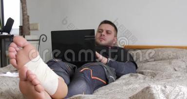 一个腿受伤的蓄胡子男人用笔记本电脑<strong>完成任务</strong>，开始在卧室里思考