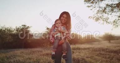 在镜头前，一位年轻的微笑的母亲和她的孩子男孩，一岁，互相拥抱，宝贝吃了一大块
