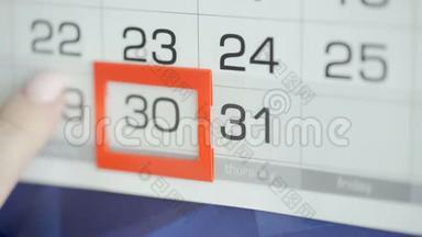 女人`在墙上的日历上交办公室更改日期。 变动30至31