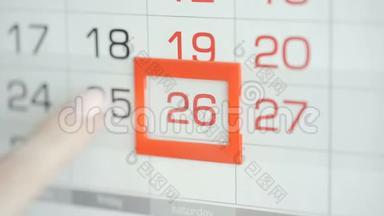 女人`在墙上的日历上交办公室更改日期。 变动25至26