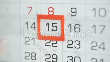 女人`在墙上的日历上交办公室更改日期。 变动14至15