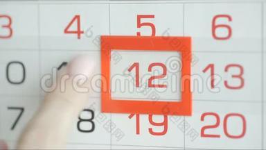 女人`在墙上的日历上交办公室更改日期。 变动11至12