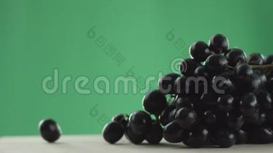在视频中，我们看到一串葡萄，两颗葡萄从一串串的绿色背景上滚动在桌子上