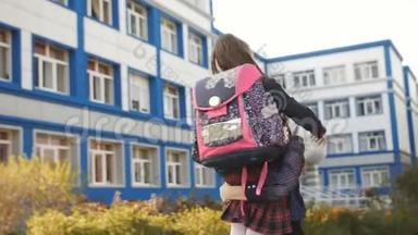母亲和女儿一起走，一个穿着校服的<strong>一年级</strong>学生和一个背包在学校大楼附近。