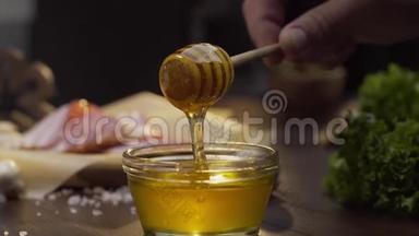 厨师蘸木蜂蜜，用液体蜂蜜粘在玻璃碗上，用蜂蜜烹饪，用天然蜂蜜做甜食