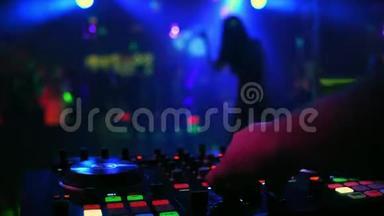 混合控制器与DJ手在夜总会与模糊的剪影跳舞女歌手