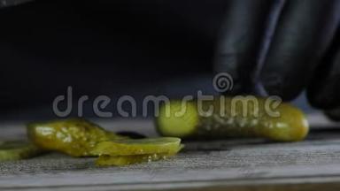 这位厨师正在剪一根咸黄瓜，这根黄瓜被放在一块<strong>木板</strong>上，上面是一块孤立的<strong>黑色背景</strong>