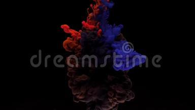 五颜六色的红色和蓝色墨水从上面混合在水中，轻轻地在黑色背景下旋转