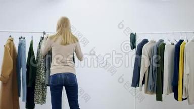 一位年轻漂亮的女售货员在试衣间展示一件外套和一件皮夹克