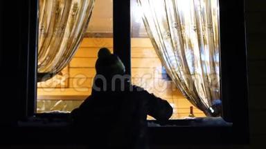 冬天的夜晚。 在靠近窗户的温暖明亮的房间里，是一个年轻人，敲着窗户。 在户外射击。