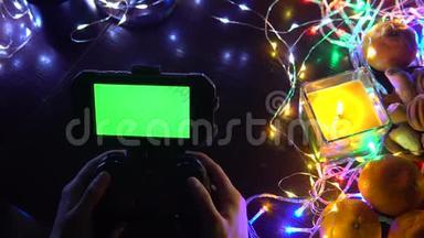 手动使用带有智能手机色度键<strong>绿色</strong>屏幕的游戏垫。 以蜡烛、花环、<strong>彩灯</strong>组成圣诞新年，