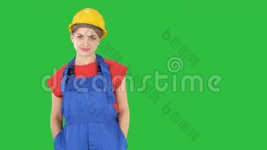 微笑的建筑工人妇女站着，变换<strong>姿势</strong>折叠双<strong>手</strong>，双<strong>手</strong>放在臀部，双<strong>手</strong>放在绿色的口袋里